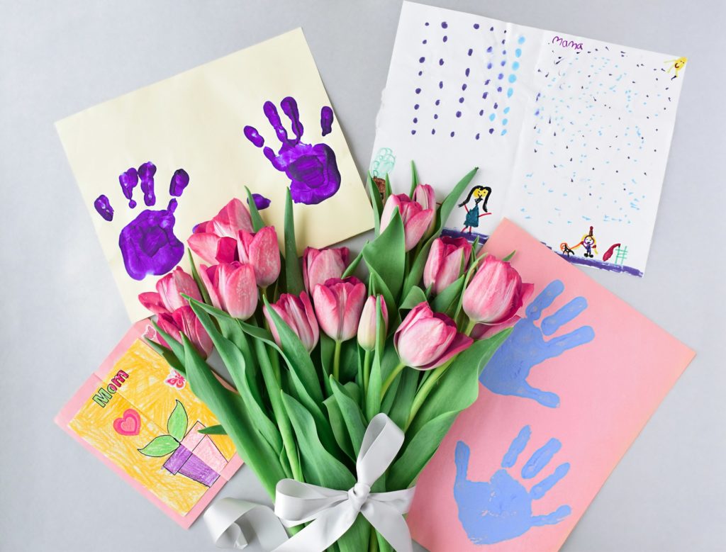 Bouquet of fresh pink tulips and child’s handmade Mother’s Day crafts and handprints