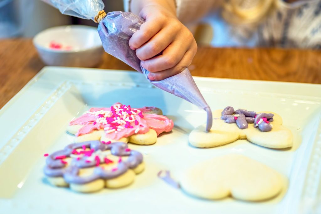 Child decorating sugar cookies with royal icing