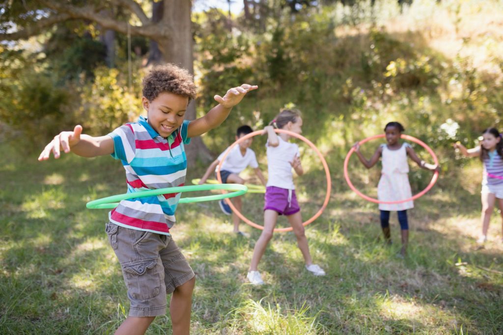 Group of friends enjoying with hula hoops at campsite
