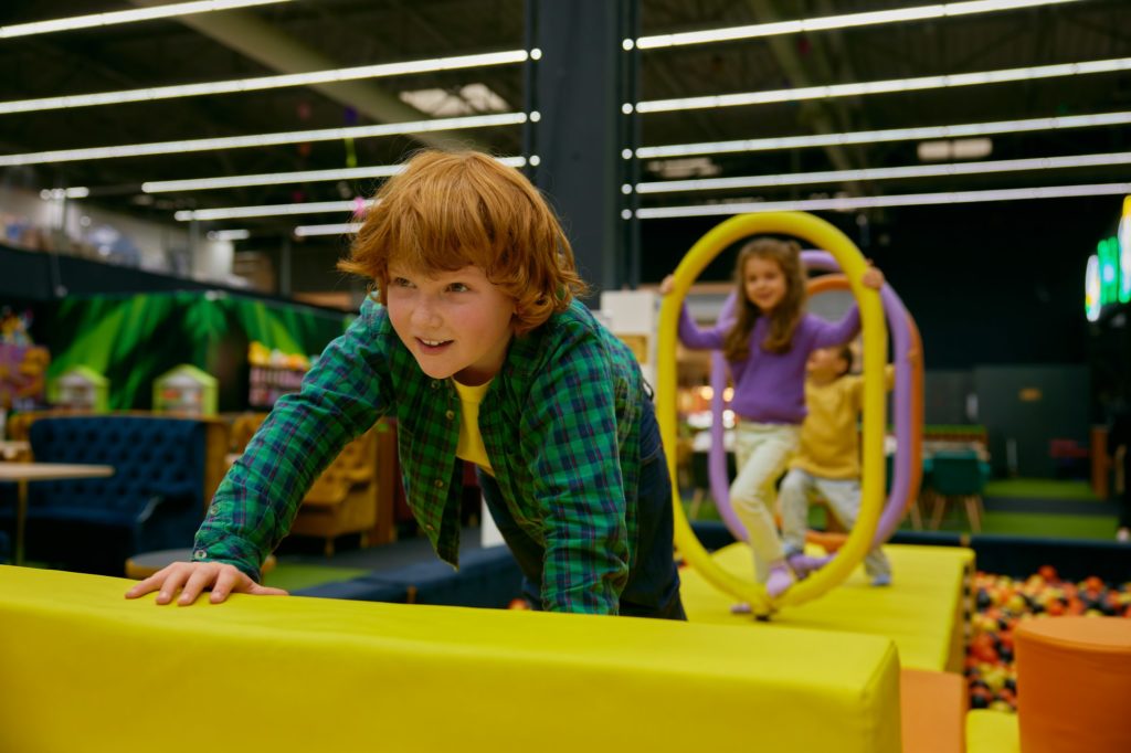 Happy children passing road of obstacles on indoor playground