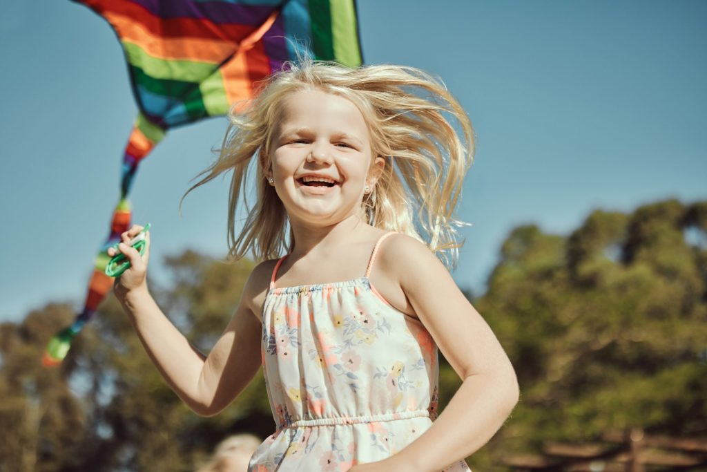 Running child, portrait and kite playing in park, nature garden or house backyard on holiday vacati